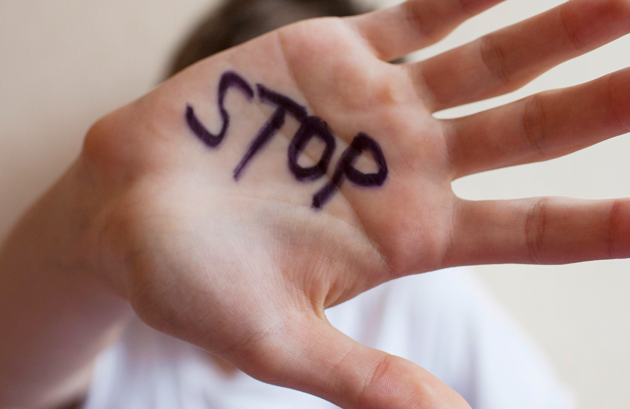 Person holding up their hand with the word "stop" written their palm.