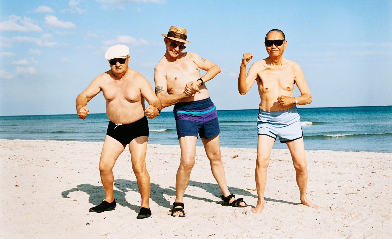 Three men posing in the sunshine on the beach.