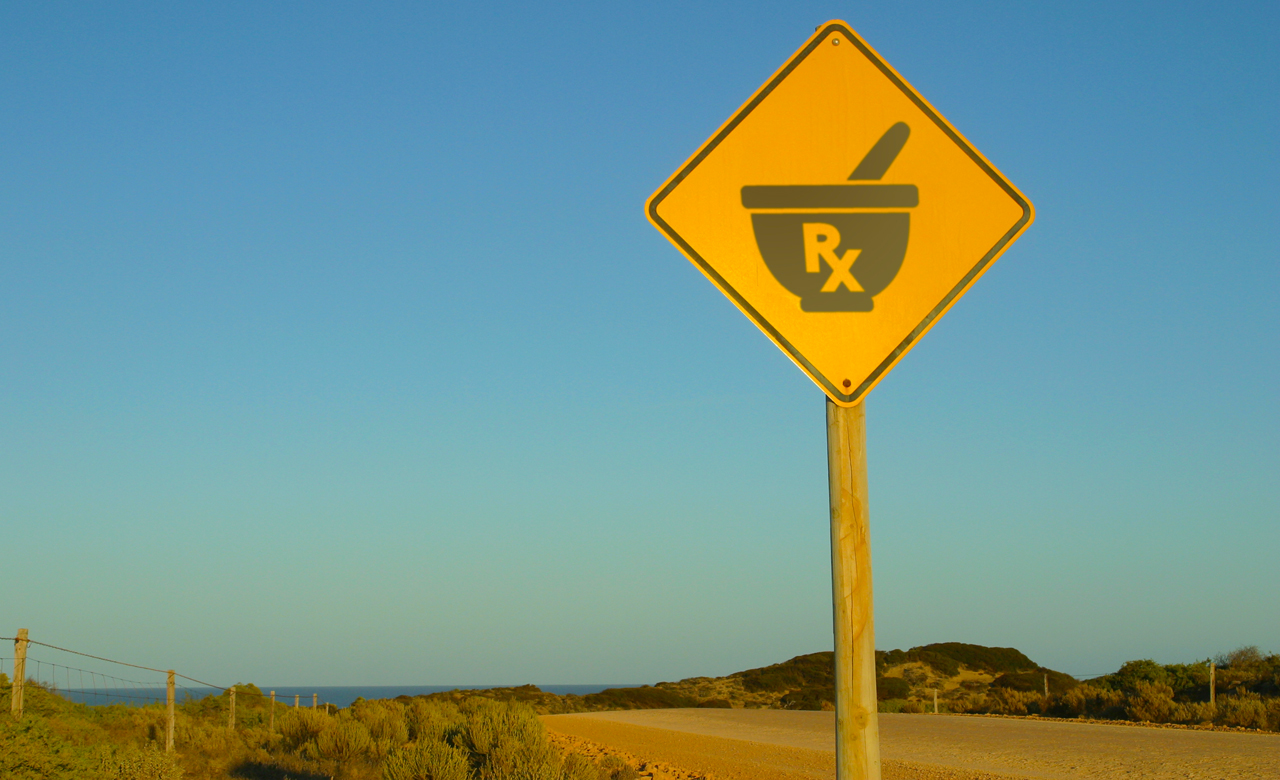 Photo illustration of rural roadway with a highway sign depicting the "Rx" and "mortar and pestle" symbols of "pharmacy".