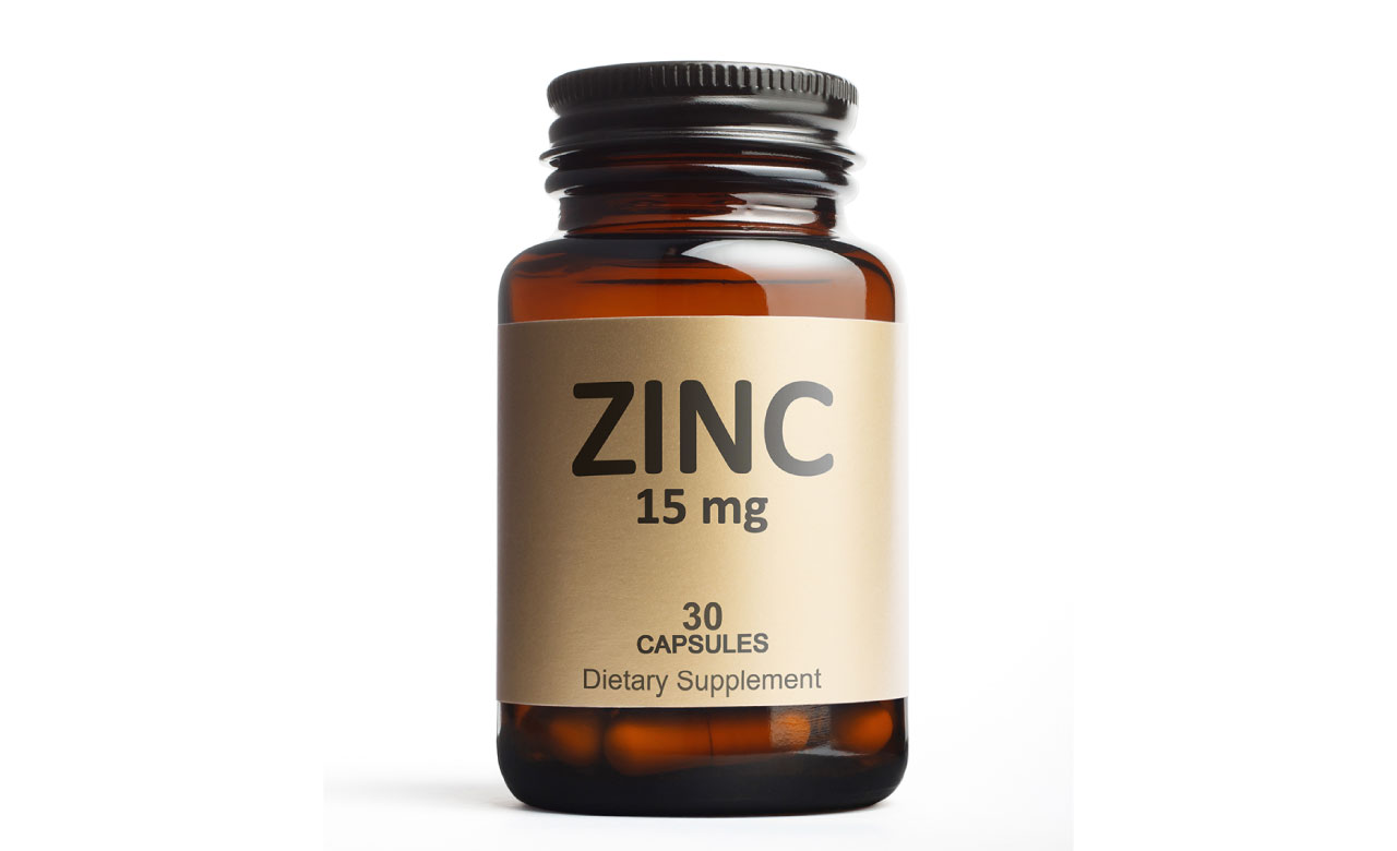 A brown glass bottle containing capsules, with a label reading "ZINC 15mg 30 capsules Dietary Supplement"