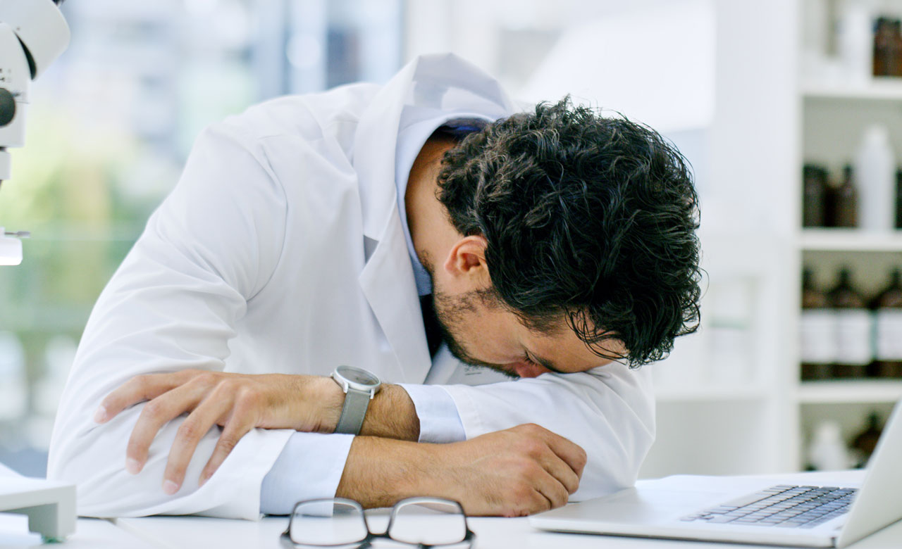 An overworked pharmacist asleep at his desk