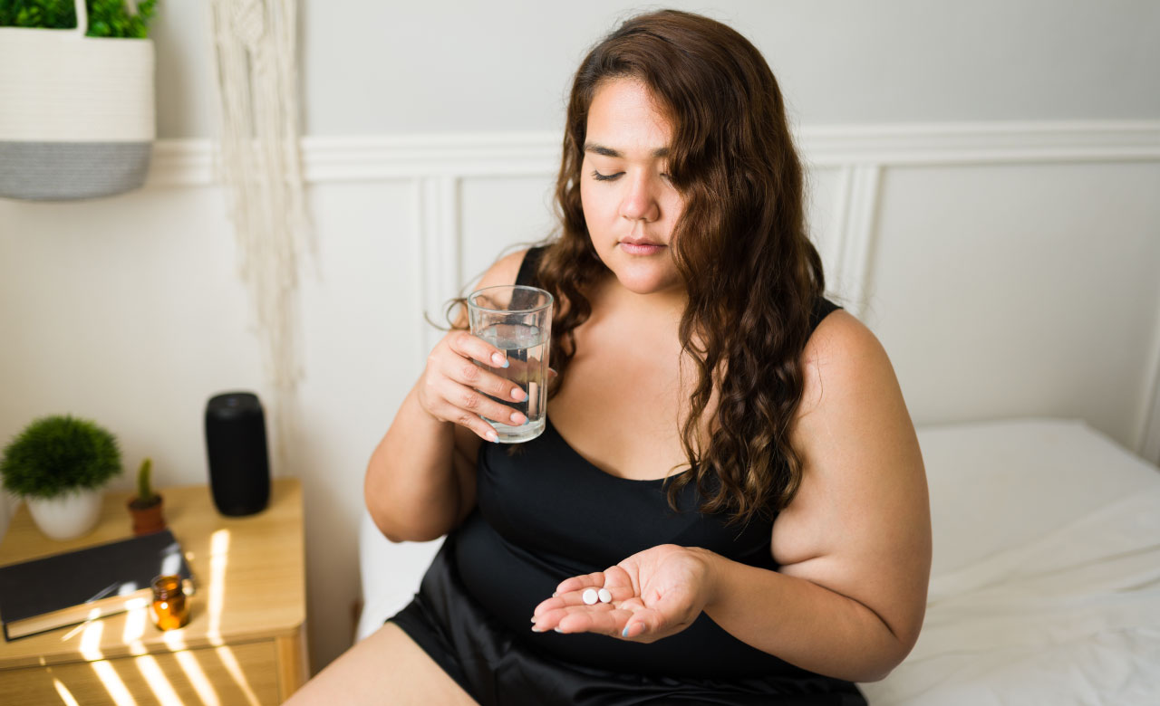 Overweight woman holing pills and a glass of water